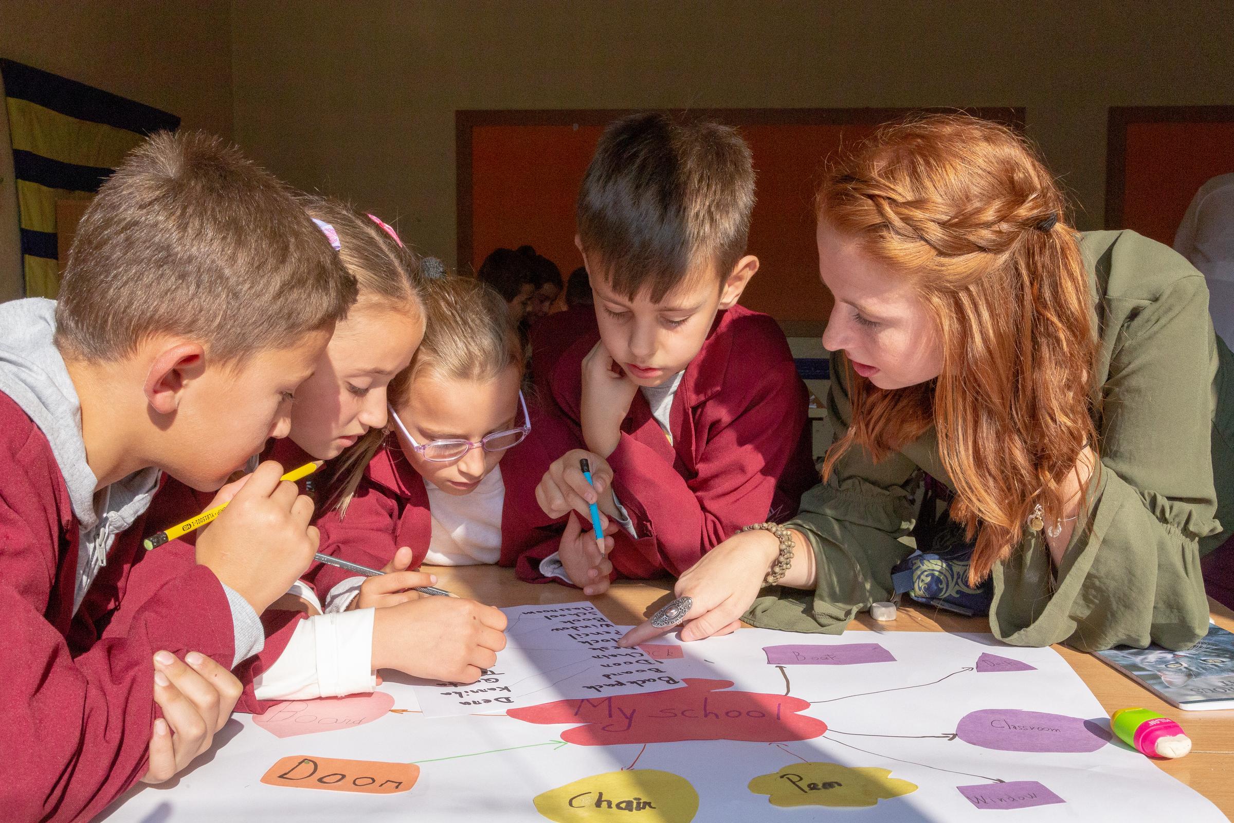 A female Peace Corps Volunteer teaching English to children in Kosovo